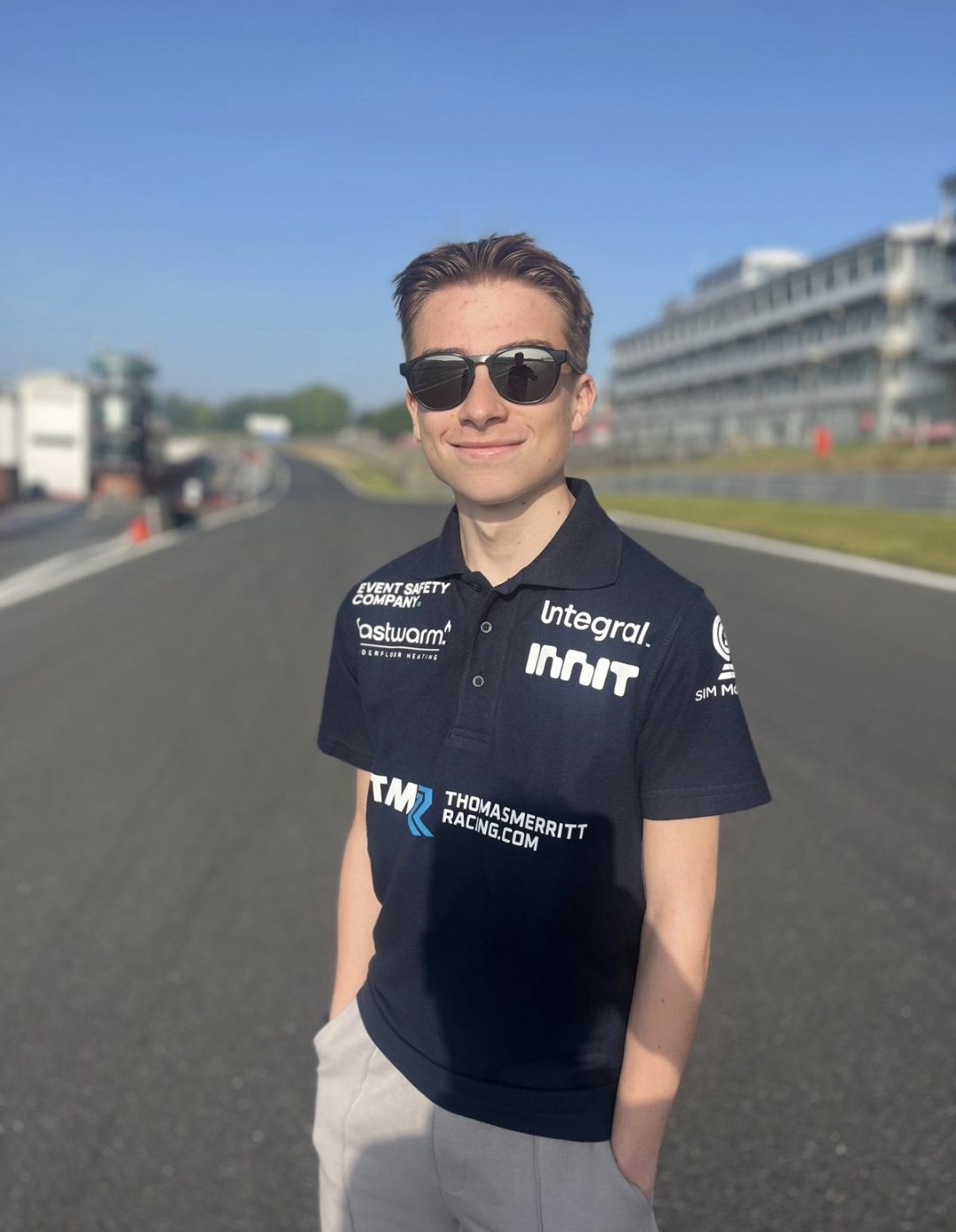 Small multi-sponsor text printed clearly on a Thomas Merritt Racing polo shirt